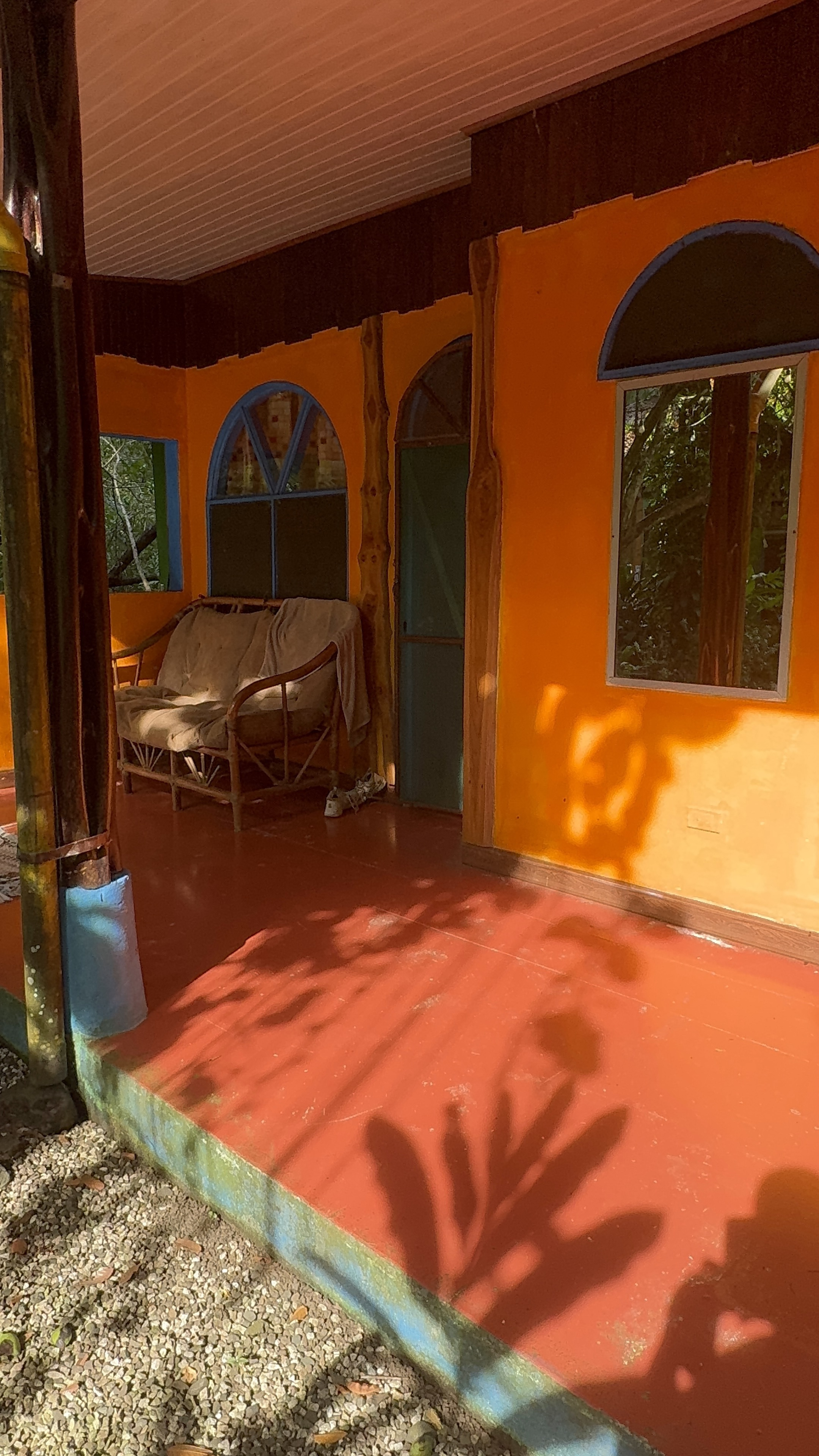 Golden morning light and leaf shadows on an orange cabin at Chosa Manglar, Costa Rica